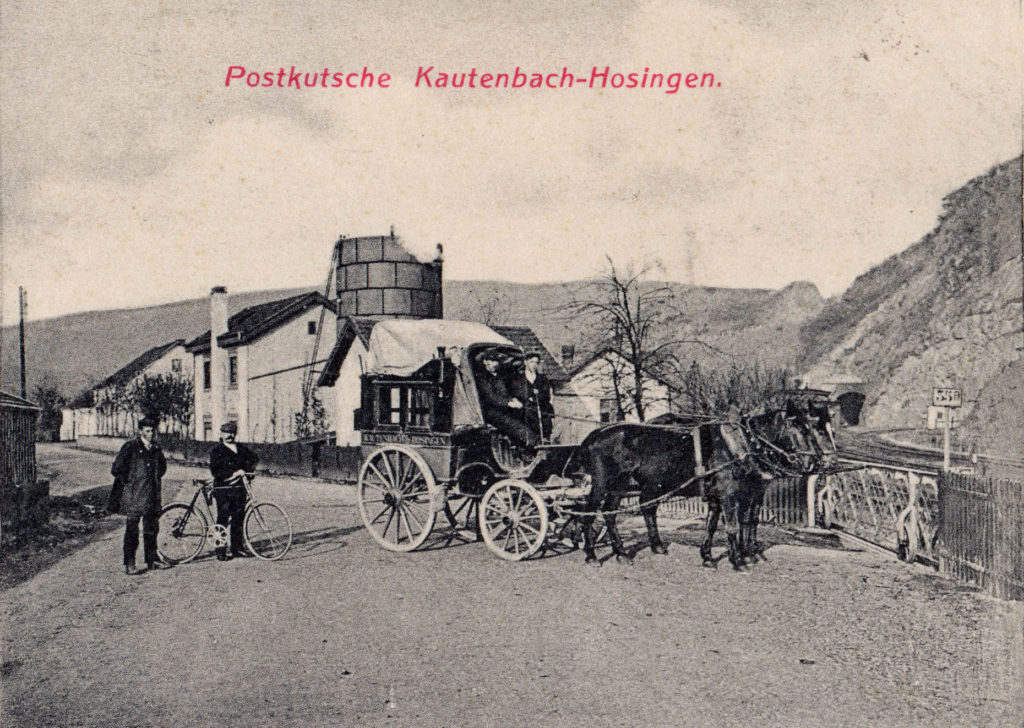 Postkutsche vor dem Bahnübergang im Bahnhof Kautenbach. Da dieser Bahnübergang nur zum Verladehof des Bahnhofs führt, ist anzunehmen dass hier nur für den Photographen posiert wurde. 
(Teil einer Ansichtskarte welche am 09.08.1912 verschickt wurde) 